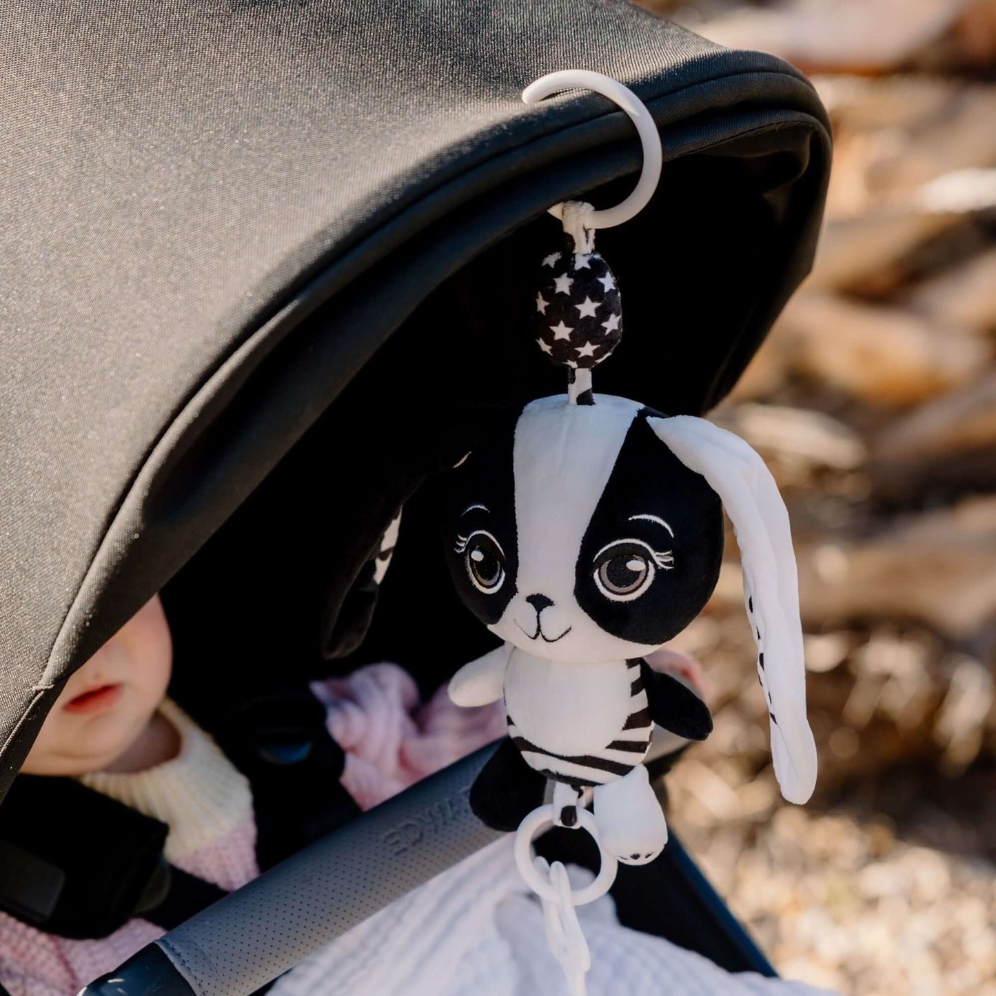 Billie the Bunny sensory toy clipped to baby car seat for on-the-go play