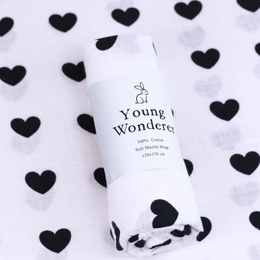White muslin wrap with 'Young Wonderer' branding on a white background with black heart patterns.